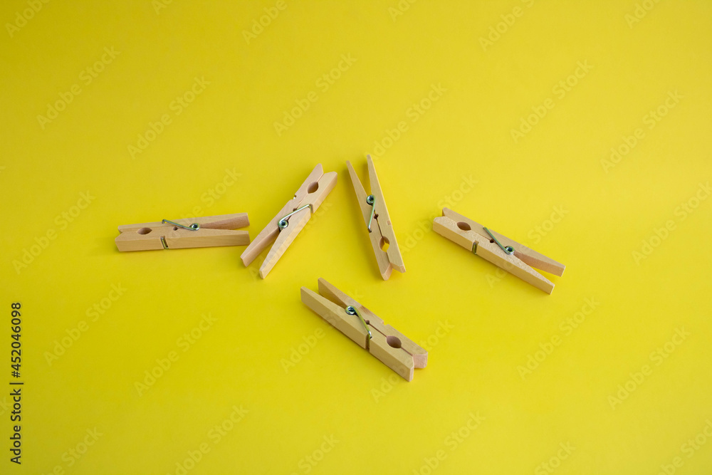 Wooden clothespins for drying clothes on a yellow background Wooden clothespins for drying clothes on a yellow background