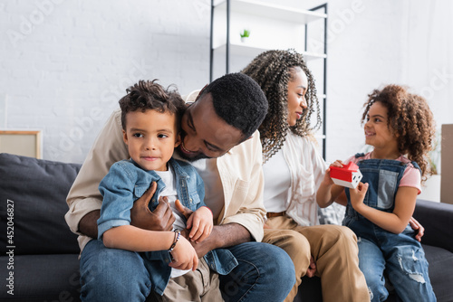 happy african american family sitting on sofa in new apartment