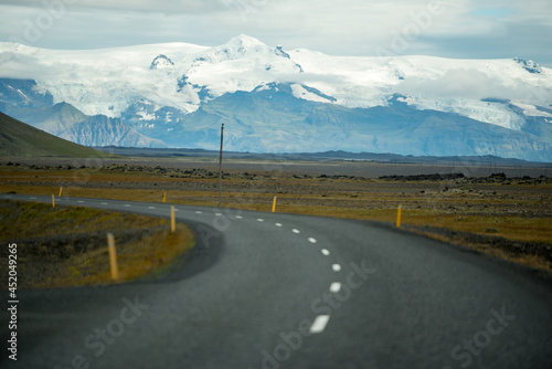 Straßenkurve mit schneebedecktem Bergmassiv im Hintergrund