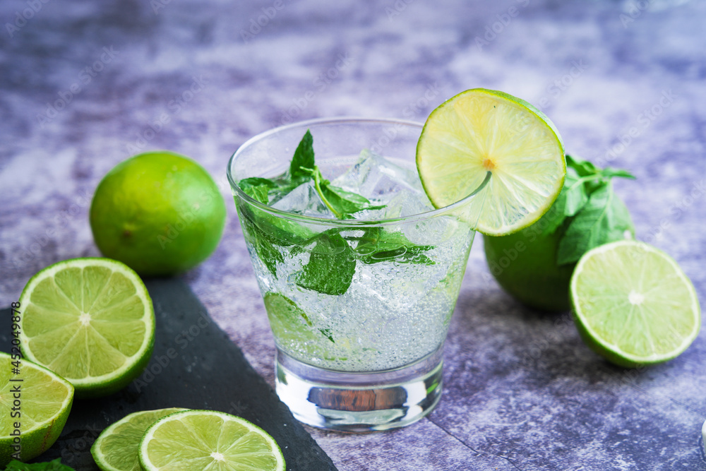Refrescante cóctel de mojito de verano con cubos de hielo, menta fresca, azucar y lima, en un vaso de cristal. Bebida de mojito exótico. Refrescante cóctel de mojito de verano con cubos de hielo, menta fresca, azucar y lima, en un vaso de cristal. Bebida de mojito exótico.