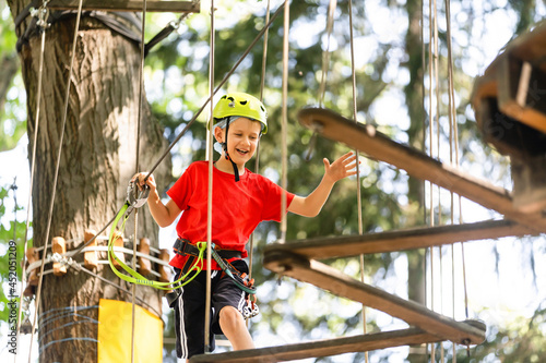 Cute school boy enjoying a sunny day in a climbing adventure activity park