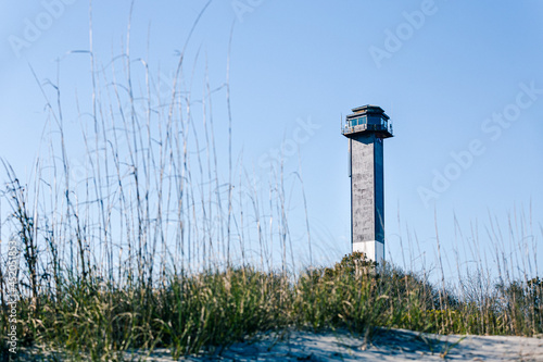 Sullivan's Island Lighthouse. Clear daytime weather. Beach dunes and grass in foreground. photo