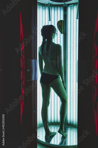 Portrait of cute elegant young woman enjoying tan in modern solarium