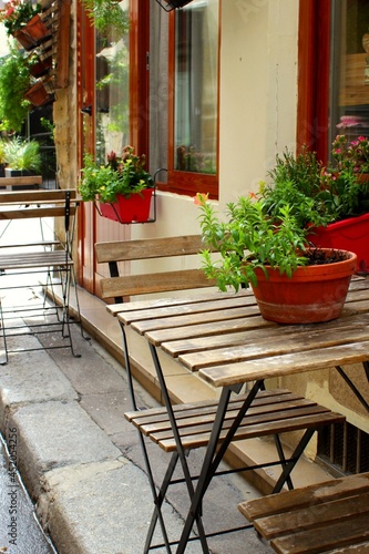 Beautiful interior of Paris cafe with summer terrace and tables with house plants in the European street  French lifestyle in Europe with authentic stylish design. Empty bistro with holiday ambiance.