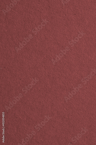The surface of dark brown cardboard. Paper texture with cellulose fibers. Vertical paperboard background or backdrop. Macro