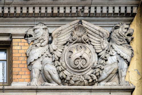 Coat of arms with two mythological winged lions on the facade of a historical red brick building in center of SPb., Russia.