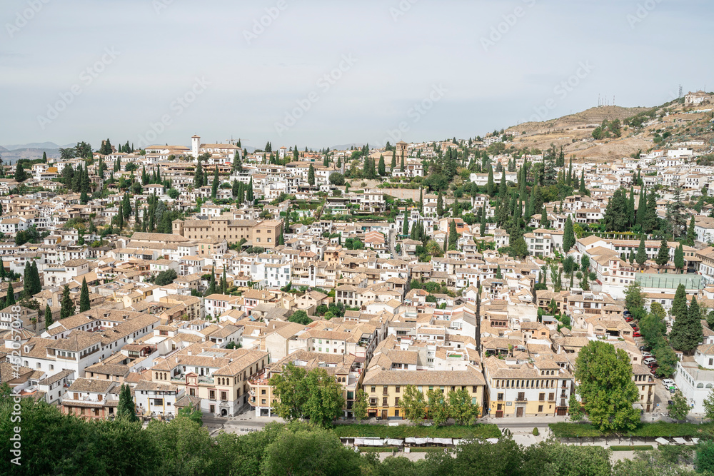 Detailed landscape photo of Albacin district, Granada old town, Andalusia, Spain 2019. White houses with tiled roofs surrounded by cypresses and other greenery