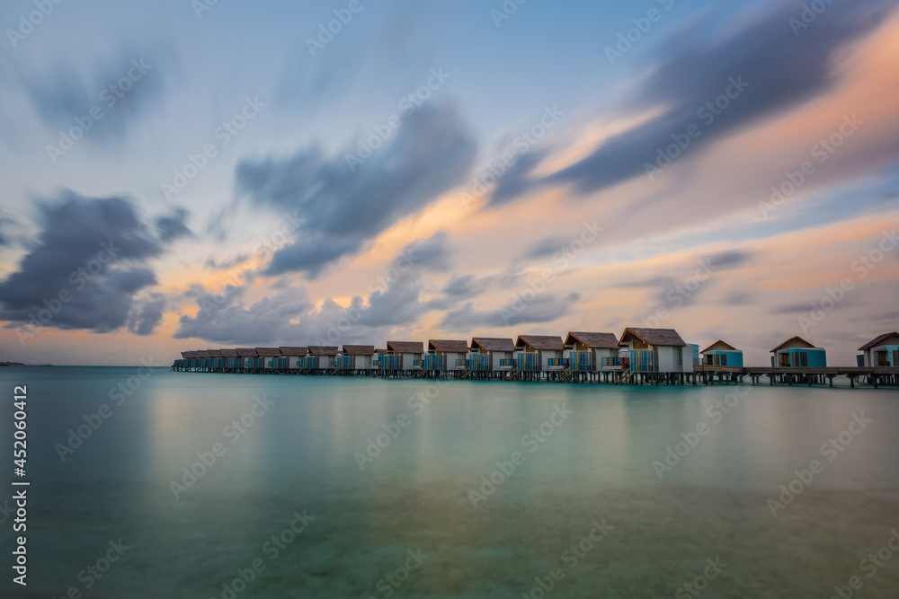 Island in ocean, overwater villas at the time sunset. Crossroads Maldives, hard rock hotel. July 2021. Long exposure picture