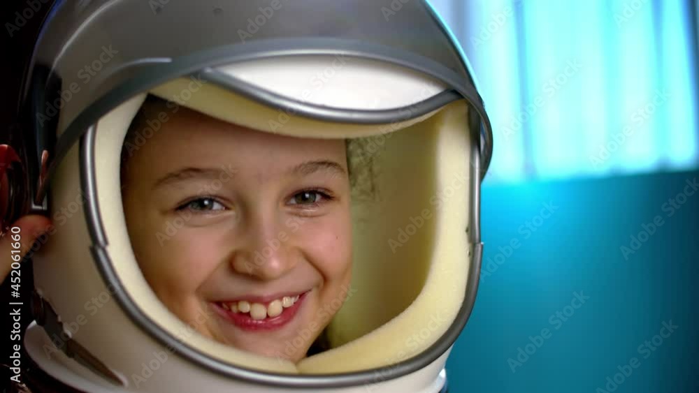 Child plays at home in an astronaut,portrait funny of a little girl 8-9 years old in a toy space helmet,smiling child looking at camera,close-up,pilot traveling into space.Concept of a happy childhood Child plays at home in an astronaut,portrait funny of a little girl 8-9 years old in a toy space helmet,smiling child looking at camera,close-up,pilot traveling into space.Concept of a happy childhood