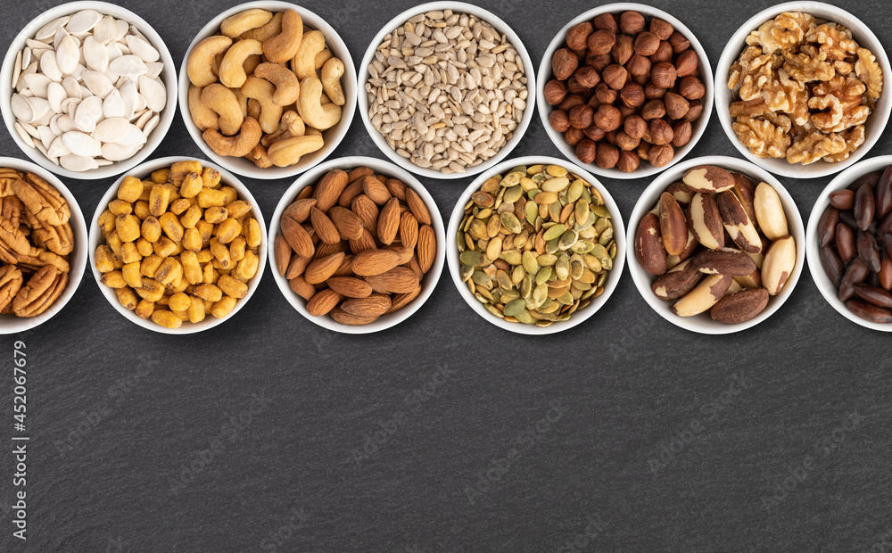 Assorted nuts and seeds in bowls over stone background with copy space Assorted nuts and seeds in bowls over stone background with copy space