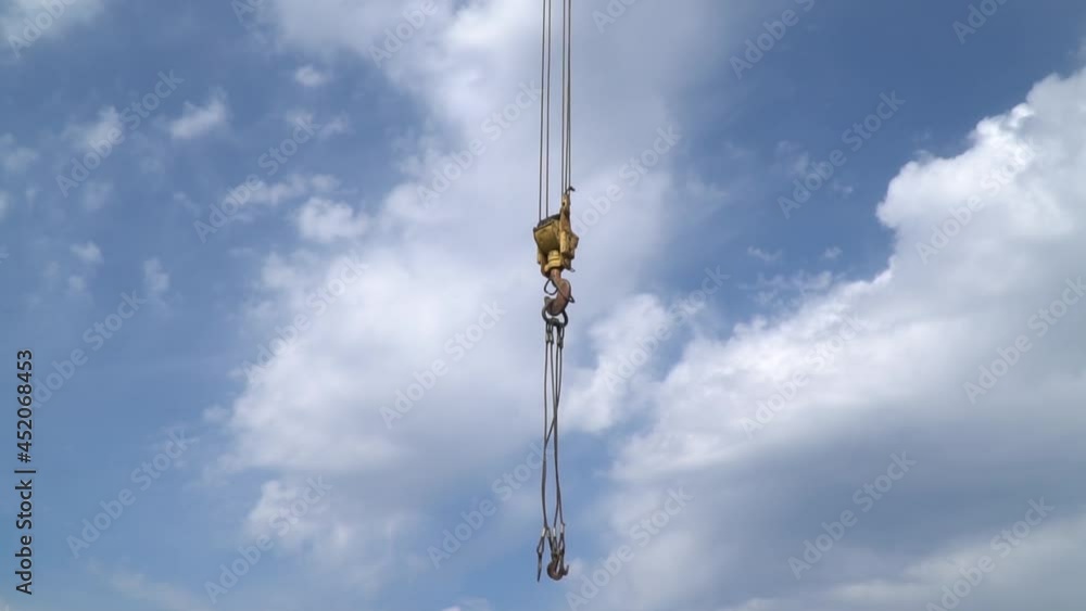 Blue sky in the background of a crane hook hanging on steel cables Blue sky in the background of a crane hook hanging on steel cables