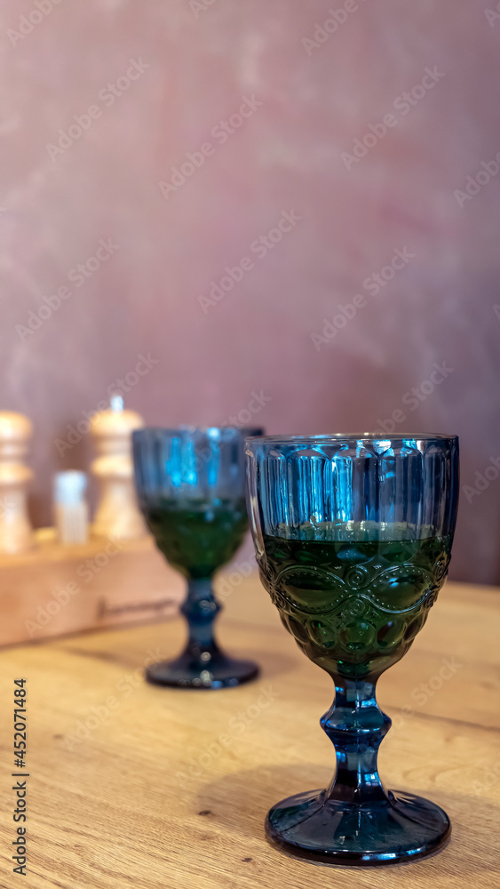Two blue glasses of wine on a table in a restaurant. Wooden table background. Two blue glasses of wine on a table in a restaurant. Wooden table background.