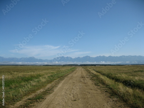 Steppe, road and mountains, blue sky. Border of Russia and Mongolia
