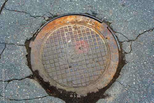 Metallic manhole cover of the city sewerage close-up.