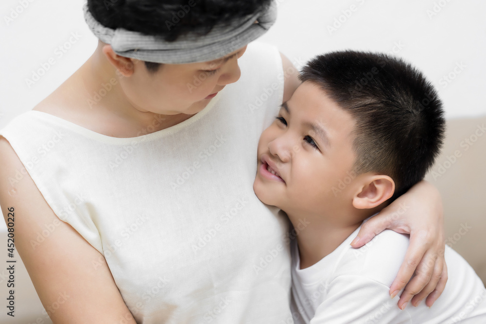 Cute Asian little boy son congratulating his mom happy with Mothers day, giving her handmade greeting postcard with red heart while sitting together on sofa at home. Family holidays concept Cute Asian little boy son congratulating his mom happy with Mothers day, giving her handmade greeting postcard with red heart while sitting together on sofa at home. Family holidays concept