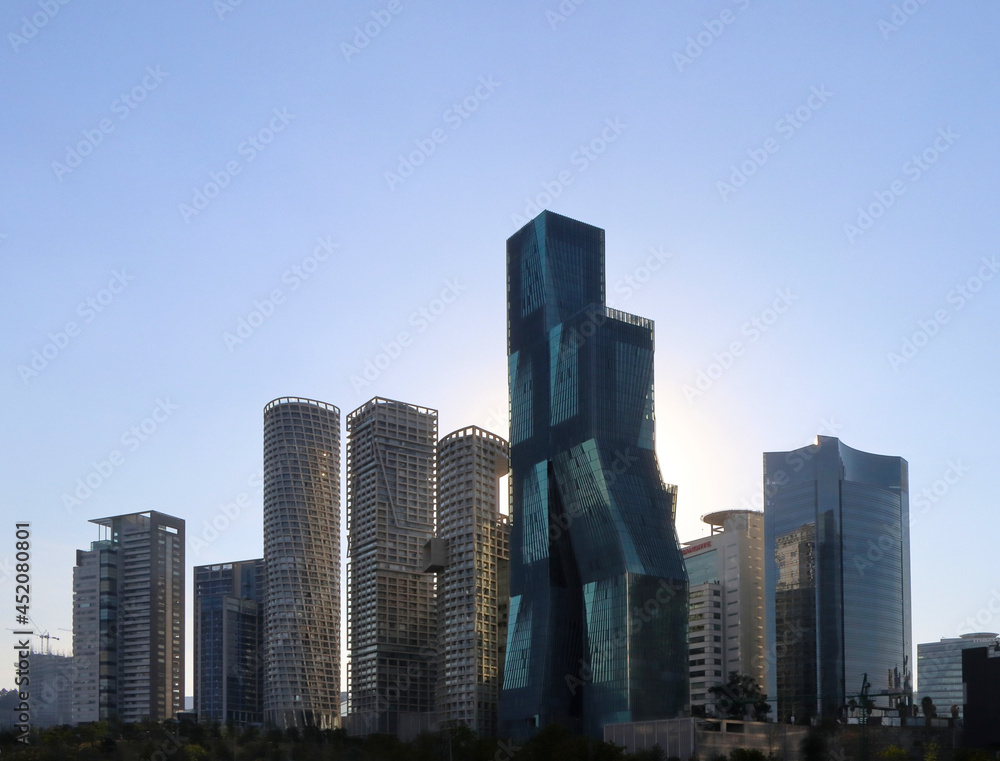 Edificios altos de arquitectura moderna con el sol poniéndose a sus espaldas y el cielo azul