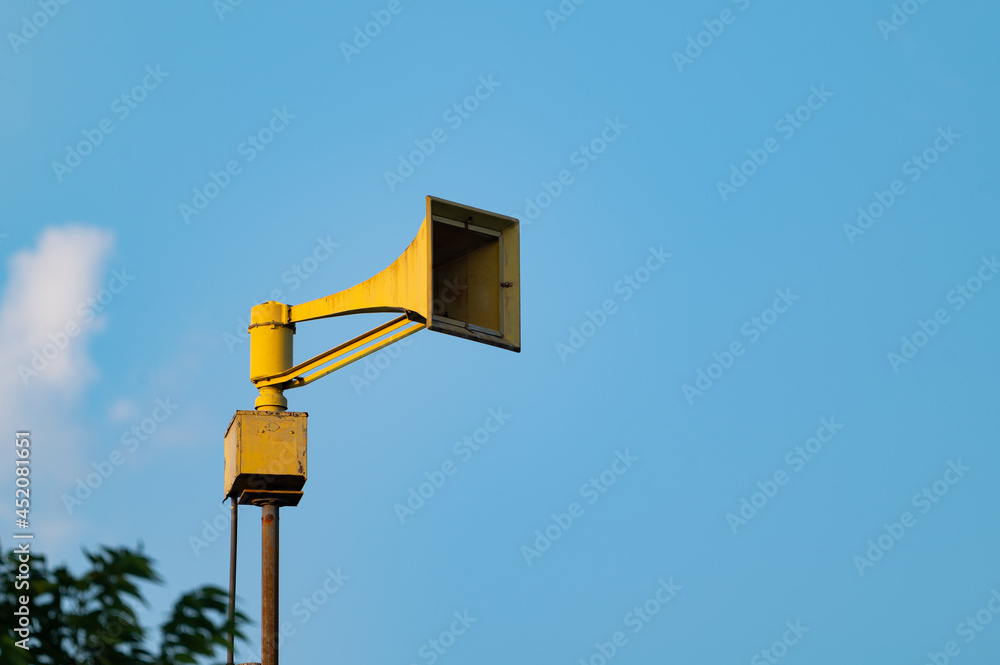 yellow warning siren with blue sky