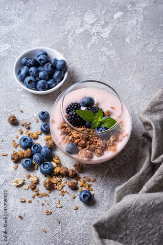 Yogurt dessert with berries, granola and mint in glass