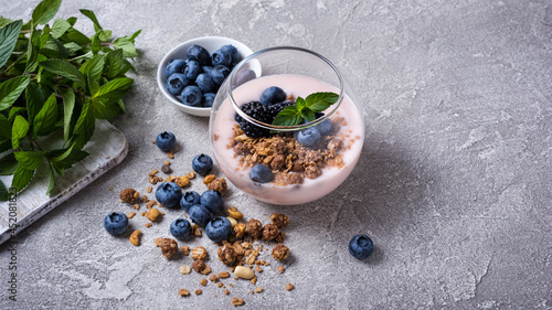 Yogurt dessert with berries, granola and mint in glass