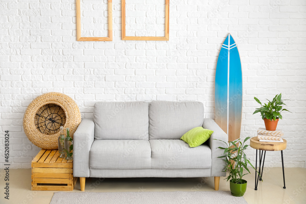 Obraz premium Interior of modern stylish room with surfboard, sofa and houseplants