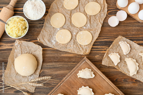 Composition with raw dumplings on wooden background
