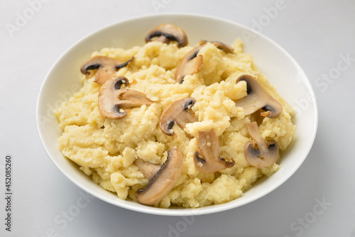 Bowl with tasty mashed potatoes and mushrooms on light background
