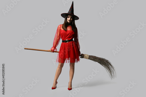 Beautiful woman dressed as witch for Halloween on light background