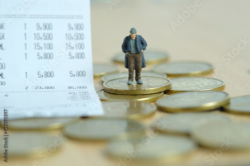 Miniature people toy figure photography. Trouble paying bills concepts. A sad man with no money standing beside receipt of payment. Image photo