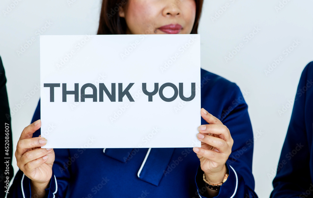 Studio shot of unrecognizable unidentified faceless female officer in business clothes holding thank you paper sign at chest showing appreciation to customers and colleagues on white background Studio shot of unrecognizable unidentified faceless female officer in business clothes holding thank you paper sign at chest showing appreciation to customers and colleagues on white background