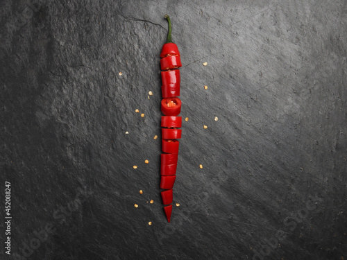 Red hot chilli pepper on dark black rough slate stone surface background