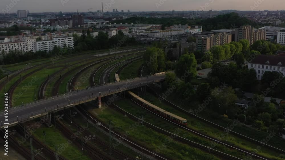Tracking of S bahn train unit turning on tracks into station. City scene lit by late evening sun. Berlin, Germany Tracking of S bahn train unit turning on tracks into station. City scene lit by late evening sun. Berlin, Germany