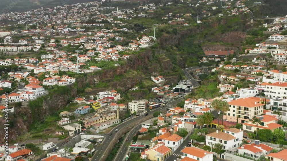 Madeira Islands, Portugal. Coastal architecture of the remote island surrounded with the gardens - top view. Drone footage of a city within volcanic landscape and lava rocks. High quality 4k footage