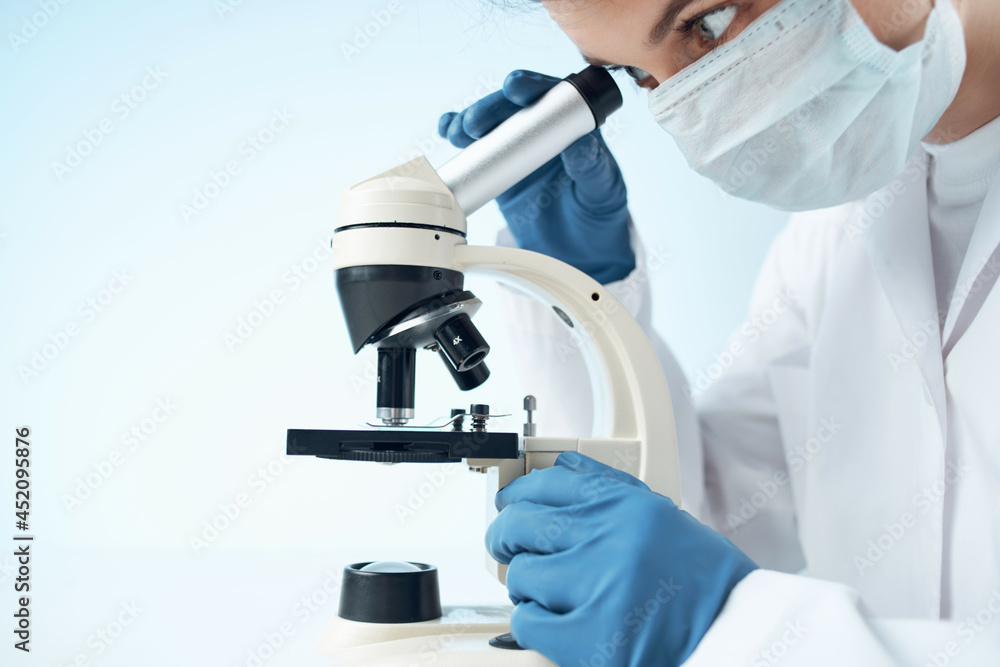 laboratory assistant wearing a medical mask looking through a microscope Professional research experiment laboratory assistant wearing a medical mask looking through a microscope Professional research experiment