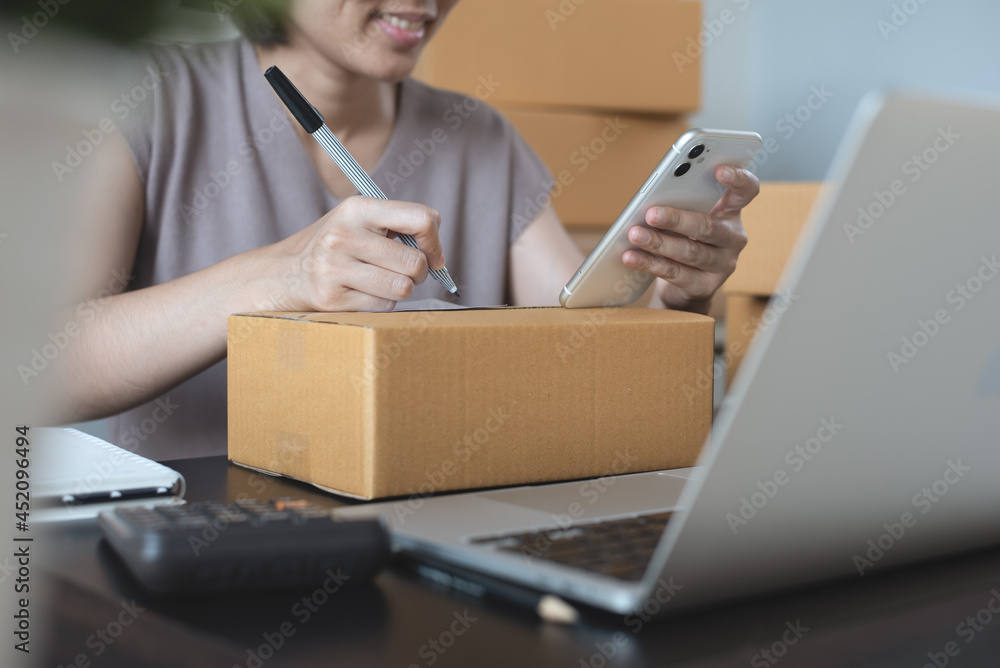 Small business, E-commerce, online market concept. Smiling young woman entrepreneur and preparing product parcels to deliver and address to customer Small business, E-commerce, online market concept. Smiling young woman entrepreneur and preparing product parcels to deliver and address to customer