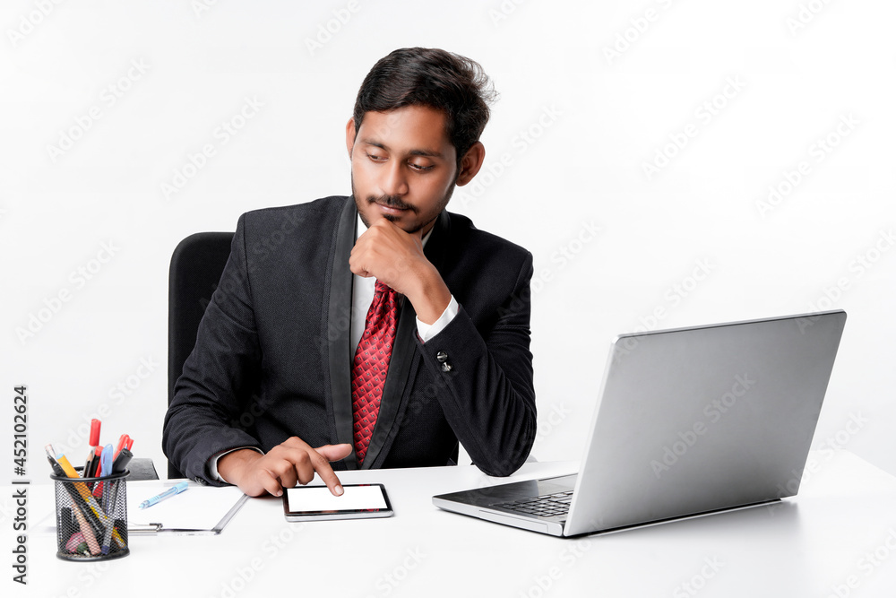 Young indian man in suit and using tablet and laptop at office Young indian man in suit and using tablet and laptop at office