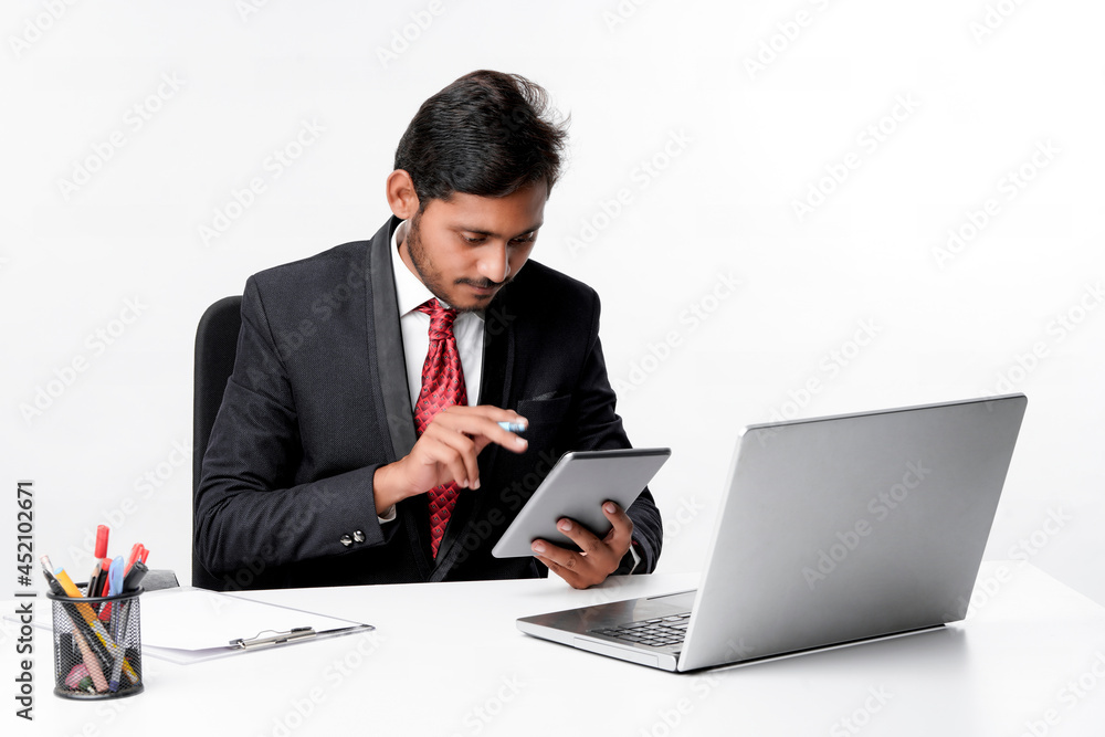 Young indian man in suit and using tablet and laptop at office Young indian man in suit and using tablet and laptop at office