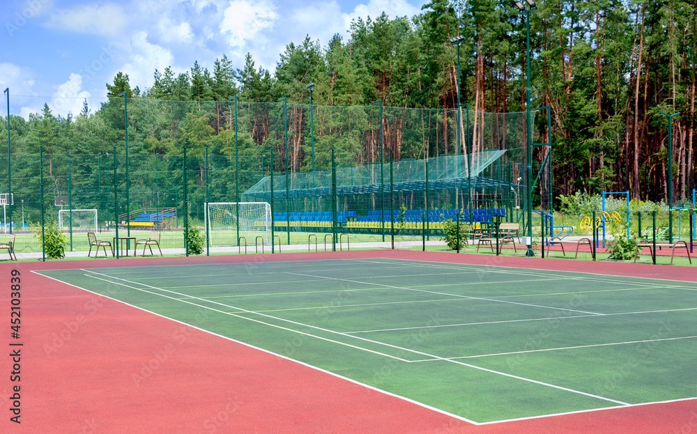 Fototapeta premium Sports ground on the outskirts of the city in a wooded area. View of the tennis court, fitness equipment, football field and others public sports grounds for team games of sport.