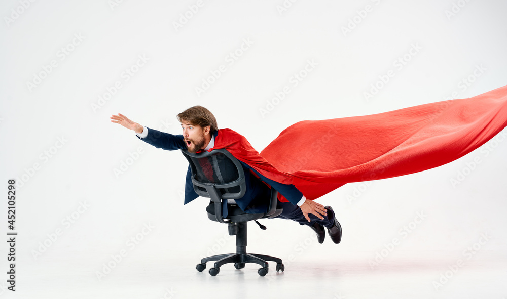business man in a suit rides in a chair with a red cloak superhero manager