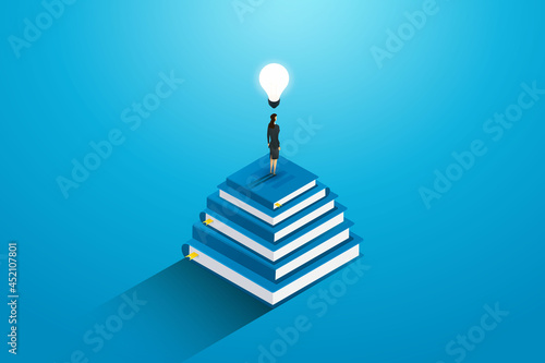 Businesswoman standing on top stack  books with lightbulbs.