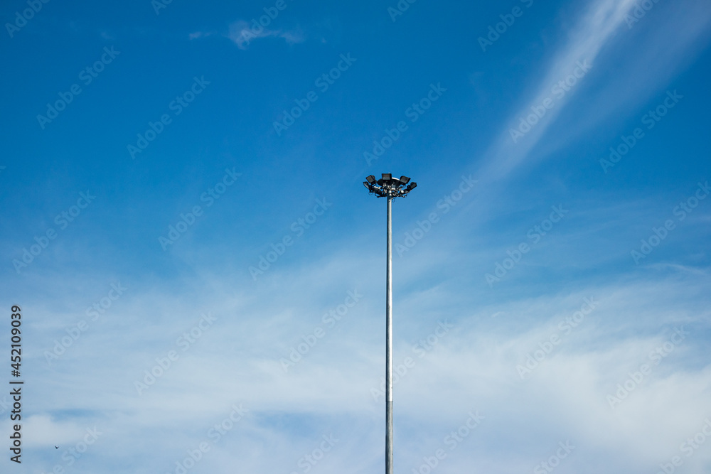 Spotlight on an aluminum pole with a background in the blue sky.