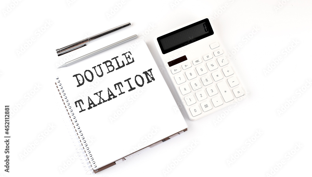 Notepad with text DOUBLE TAXATION with calculator and pen. White background. Business concept Notepad with text DOUBLE TAXATION with calculator and pen. White background. Business concept