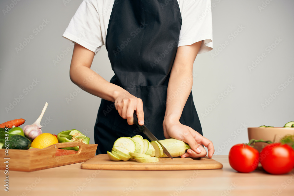 Woman in black apron slicing vegetables kitchen cooking food