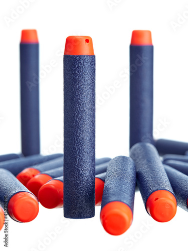 Close-up of a scattering of toy plastic cartridges for pneumatic weapons in blue with an orange tip, isolated on a white background.