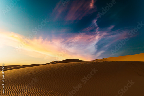 (Selective focus) Stunning sunset over some sand dunes of the Merzouga desert in Morocco. Merzouga is a small village in southeastern Morocco. Natural background with copy space.