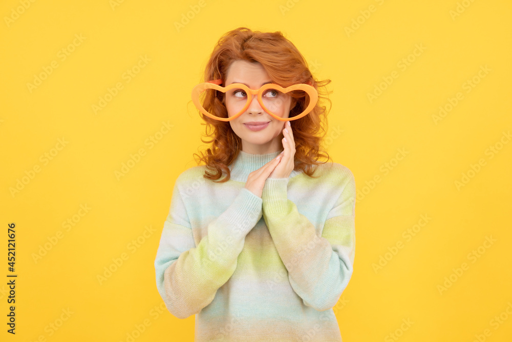 happy redhead woman wear funny party glasses on yellow background, party