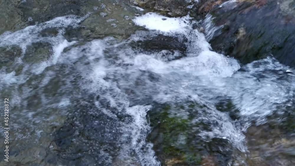 A raging mountain river in close-up. The purest water flows down the stones in a strong stream. The river flows rapidly from the winter melting of snow. The concept of nature ecology, water resources A raging mountain river in close-up. The purest water flows down the stones in a strong stream. The river flows rapidly from the winter melting of snow. The concept of nature ecology, water resources