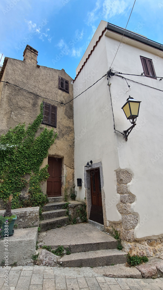 Ivy-covered entrance to an old house and a lantern on the wall in the old city in southern Europe in summer