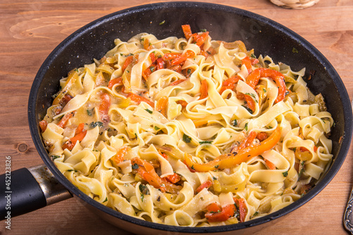 Fettuccine pasta with creamy bell pepper sauce in a pan, close-up