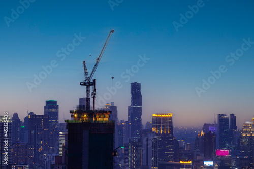 silhouete photo of Hight rising crane working on building with sunset twilight sky background