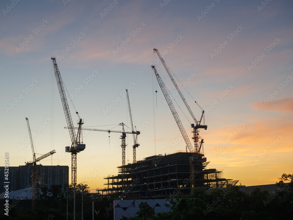 silhouete photo of Hight rising crane working on building with sunset sky background